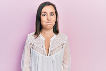 Fototapeta premium Middle age hispanic woman wearing casual clothes puffing cheeks with funny face. mouth inflated with air, crazy expression.
