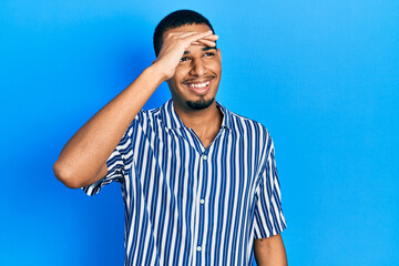 Young african american man wearing casual clothes very happy and smiling looking far away with hand over head. searching concept.