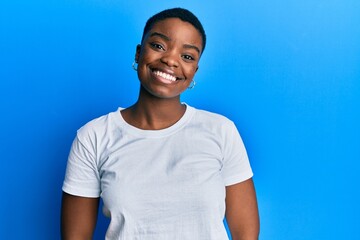 Young african american woman wearing casual white t shirt with a happy and cool smile on face....