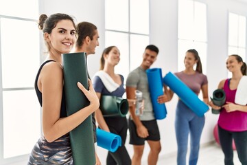 Group of young sporty people standing at sport center. Hispanic woman smiling happy looking at the camera.