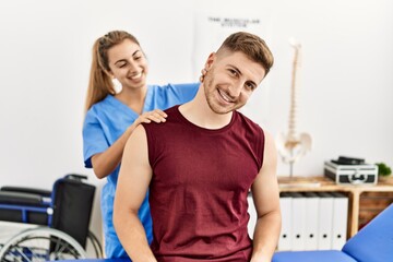 Fototapeta premium Young hispanic physioterapist woman make neck rehab treatment to man at the clinic.