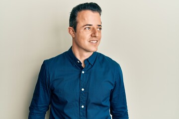 Handsome young man wearing business shirt looking to side, relax profile pose with natural face and confident smile.