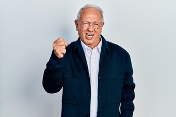 Senior man with grey hair wearing casual style and glasses angry and mad raising fist frustrated and furious while shouting with anger. rage and aggressive concept.