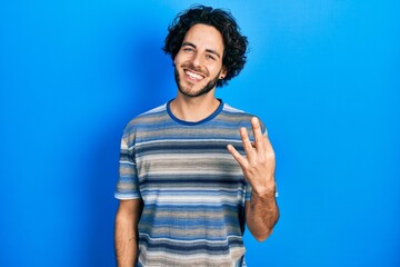 Handsome hispanic man wearing casual clothes over pink background showing and pointing up with fingers number three while smiling confident and happy.