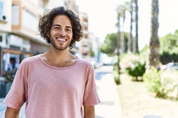 Young hispanic man smiling happy standing at street of city.