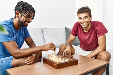 Two men friends playing chess sitting on sofa at home