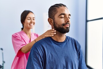 Man and woman wearing physiotherapist uniform having rehab session massaging neck at physiotherpy clinic
