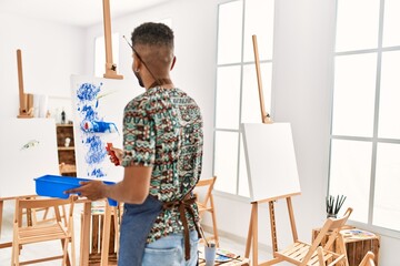 Young african american artist man on back view painting with paint roller at art studio.