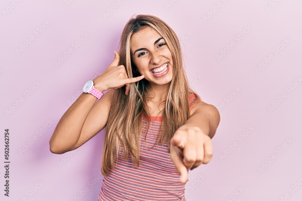 Sticker Beautiful hispanic woman wearing casual summer t shirt smiling doing talking on the telephone gesture and pointing to you. call me.