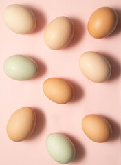 Colorful pattern made of natural organic eggs on pastel light pink background. Creative minimalistic Easter concept.
