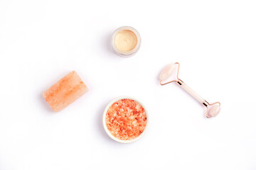 Fototapeta na wymiar Himalayan pink salt for skrub, crystal rose quartz facial roller, handmade soap bar and cream in a jar. Natural skin care products isolated on white background. Top view, flat lay, copy space