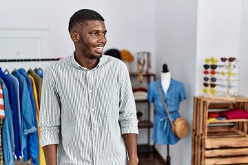Fototapeta premium Young african american man working as manager at retail boutique looking away to side with smile on face, natural expression. laughing confident.