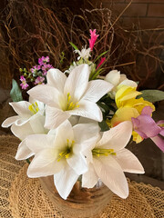 A bouquet of artificial flowers in white, yellow and pink