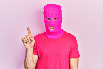 Young hispanic man with modern dyed hair wearing pink balaclava mask face smiling with an idea or question pointing finger up with happy face, number one