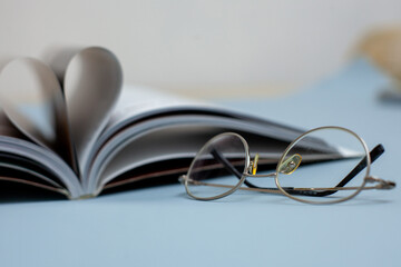 book with glasses pages in the shape of a heart on a gray background