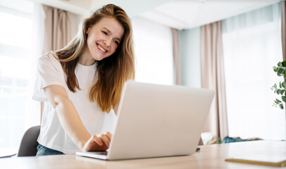 Fototapeta premium Online training uses a laptop computer. A woman at home finances and budget. Video call online.