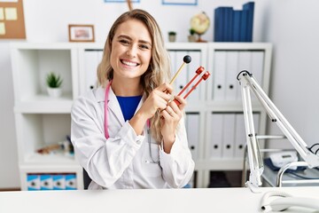 Young beautiful doctor woman holding diapason instrument smiling with a happy and cool smile on face. showing teeth.