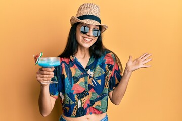 Young hispanic woman wearing summer style drinking tropical cocktail with alcohol celebrating achievement with happy smile and winner expression with raised hand