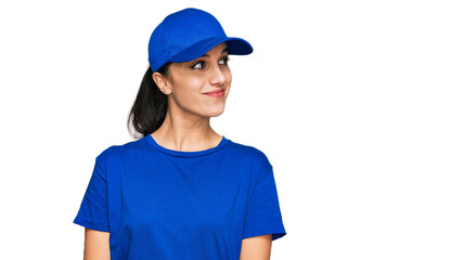 Young hispanic girl wearing delivery courier uniform smiling looking to the side and staring away thinking.