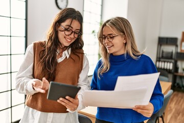 Two business workers woman reading paperwork using touchpad at the office.