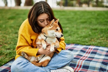 Beautiful young woman kissing and hugging shiba inu dog at park