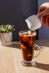 Ice coffee wooden table pouring milk creamer