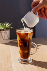 Ice coffee wooden table pouring milk creamer