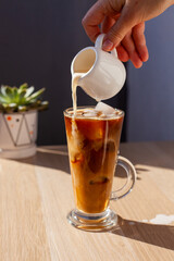 Ice coffee wooden table pouring milk creamer
