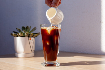 Ice coffee wooden table pouring milk creamer