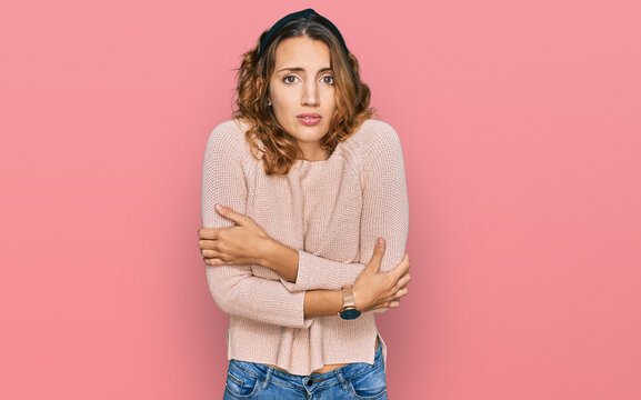 Beautiful young caucasian woman wearing casual sweater shaking and freezing for winter cold with sad and shock expression on face