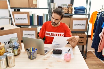 Handsome hispanic man working as volunteer doing countability at donation stand