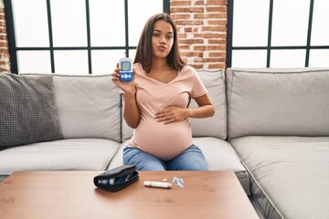 Young pregnant woman checking blood sugar looking at the camera blowing a kiss being lovely and sexy. love expression.