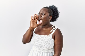 Fototapeta na wymiar Young african woman standing over white isolated background shouting and screaming loud to side with hand on mouth. communication concept.