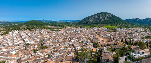 Naklejka premium Aerial view of Pollenca, Mallorca, Spain. Small town with a view into a green and rocky landscape.