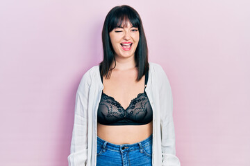 Young hispanic woman wearing lingerie winking looking at the camera with sexy expression, cheerful...
