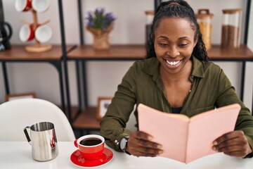 African american woman smiling confident reading book at home