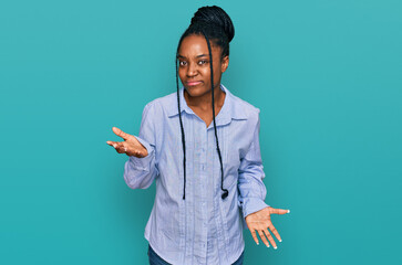 Young african american woman wearing casual clothes clueless and confused expression with arms and...