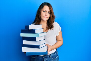 Young caucasian woman holding a pile of books skeptic and nervous, frowning upset because of problem. negative person.