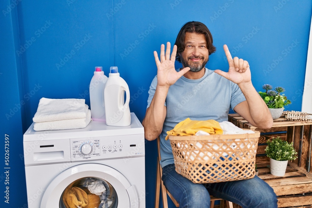 Sticker handsome middle age man waiting for laundry showing and pointing up with fingers number seven while 