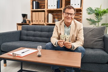 Middle age man having psychology session holding dollars at clinic