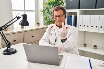 Senior doctor man working on online appointment showing middle finger, impolite and rude fuck off expression