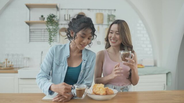 Holiday concept of 4k Resolution. Asian women having coffee together in the kitchen. Young women are in a mutual lesbian love relationship.