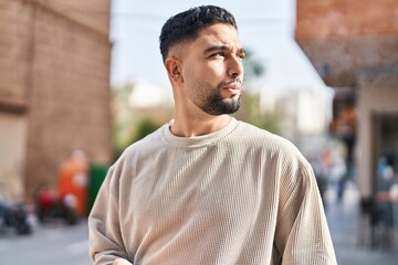 Young arab man with relaxed expression standing at street