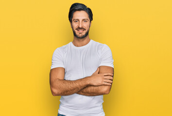 Young hispanic man wearing casual white t shirt happy face smiling with crossed arms looking at the camera. positive person.