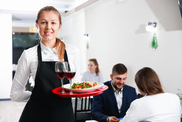 Portrait of welcoming female waiter who is standing in restaurante indoor.