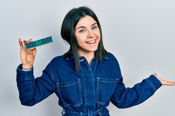 Young brunette woman holding computer ram celebrating achievement with happy smile and winner...