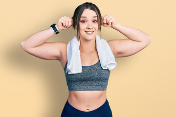 Young hispanic girl wearing sportswear and towel smiling pulling ears with fingers, funny gesture....