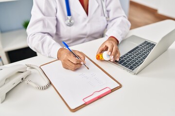 Middle age hispanic woman wearing doctor uniform prescribe pills at clinic