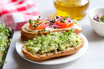 Homemade bruschetta with avocado, tomatoes and microgreens close-up. Healthy food. Tasty appetizer, snack or breakfast. Selective focus