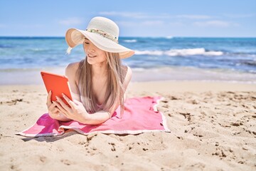 Fototapeta na wymiar Young chinese girl wearing bikini using touchpad at the beach.